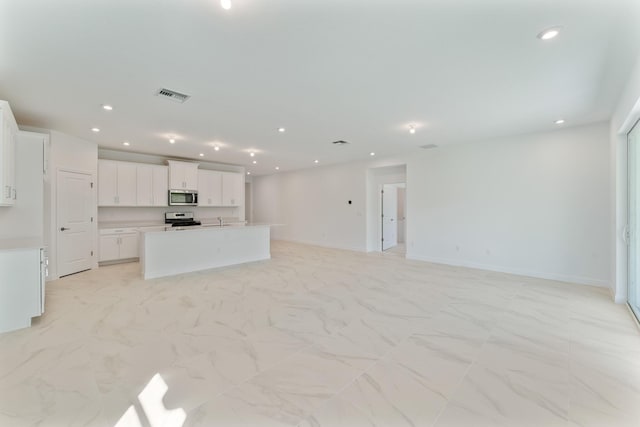 kitchen with a kitchen island with sink, white cabinets, and appliances with stainless steel finishes