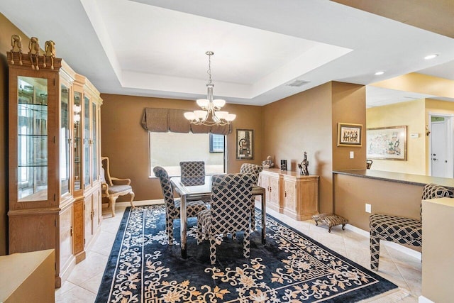 tiled dining area with a raised ceiling and a notable chandelier