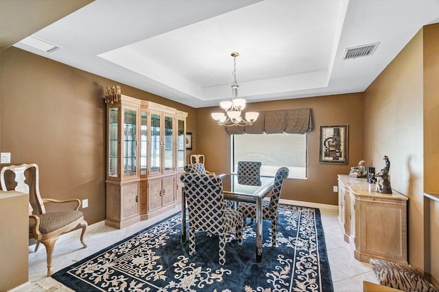 dining space with light tile patterned floors, a tray ceiling, and an inviting chandelier