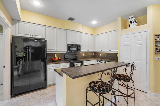 kitchen featuring white cabinetry, a breakfast bar area, and black appliances