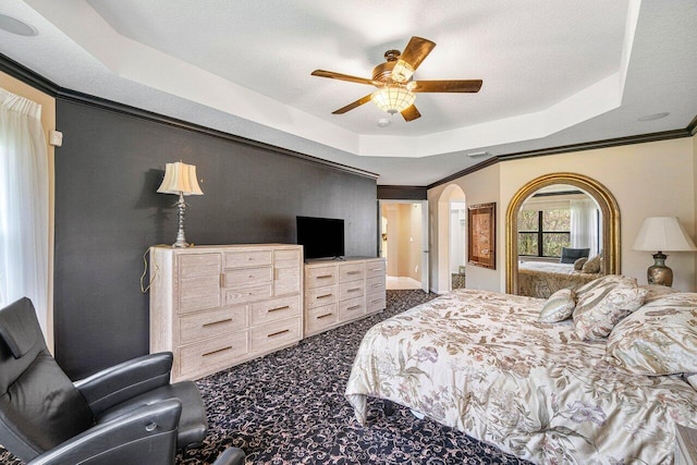 carpeted bedroom featuring a tray ceiling, ceiling fan, crown molding, and a textured ceiling