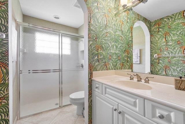 bathroom featuring tile patterned flooring, vanity, toilet, and an enclosed shower