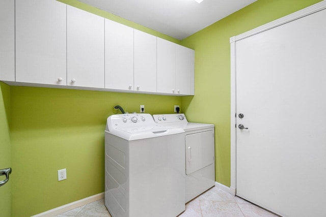 laundry area featuring washer and clothes dryer, light tile patterned floors, and cabinets