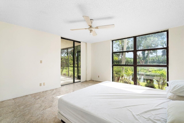 bedroom with ceiling fan, access to outside, a textured ceiling, and a wall of windows