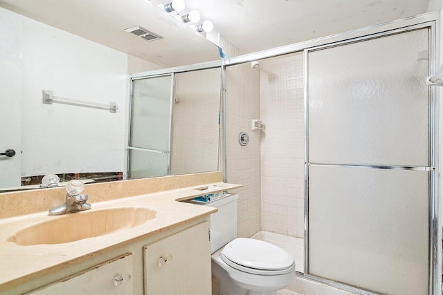 bathroom with vanity, a shower with door, and toilet