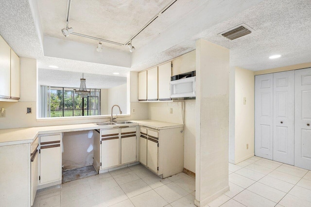 kitchen featuring cream cabinetry, sink, a textured ceiling, and light tile patterned floors