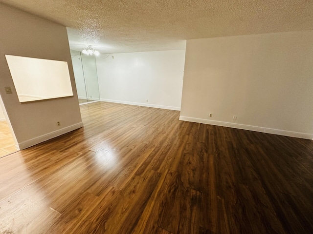 unfurnished room with wood-type flooring, a notable chandelier, and a textured ceiling