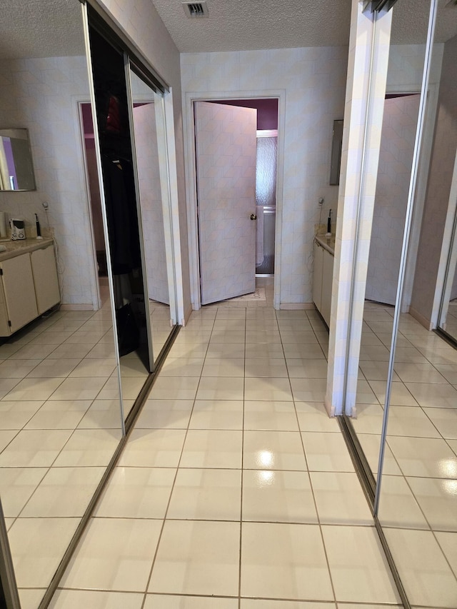 hallway featuring light tile patterned floors and a textured ceiling