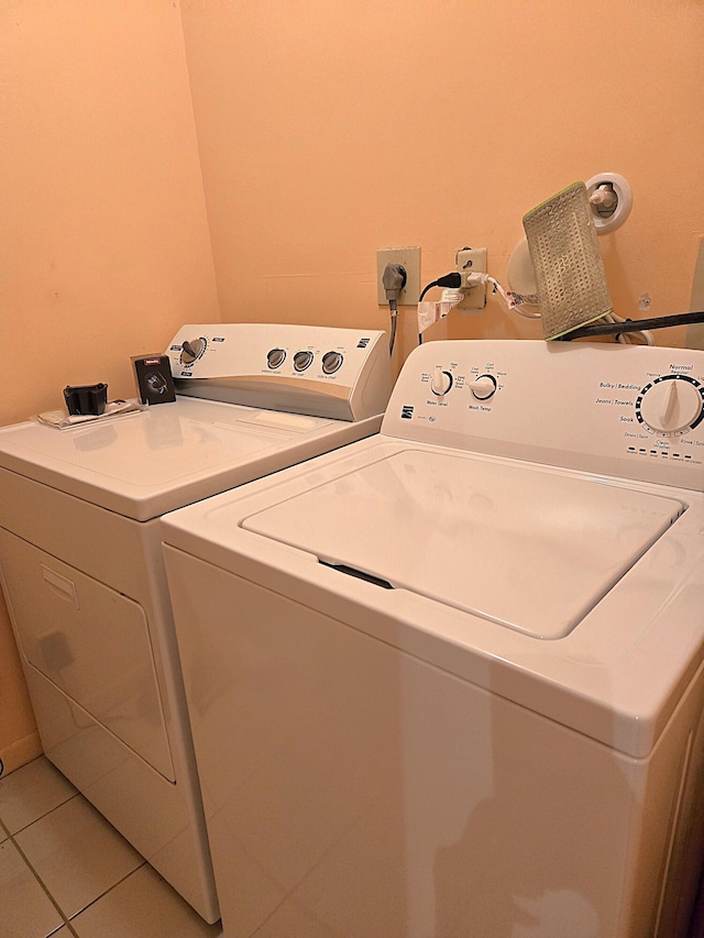 laundry area with independent washer and dryer and light tile patterned floors