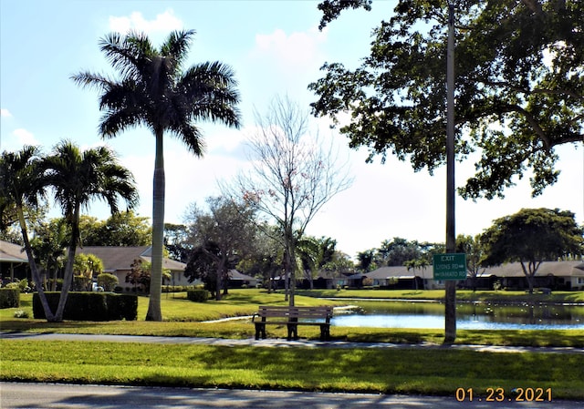 view of home's community with a water view and a yard