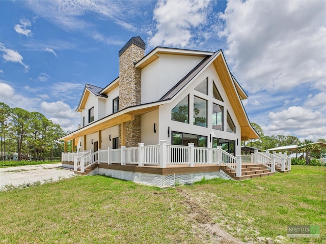 13613 157th Ct N, Jupiter, FL 33478 - back of house featuring stucco siding, covered porch, a chimney, stone siding, and a lawn