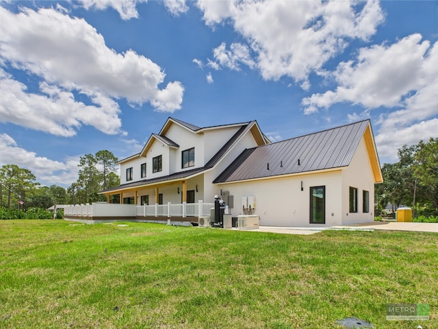 13613 157th Ct N, Jupiter, FL 33478 - rear view of property featuring stucco siding, metal roof, and a yard