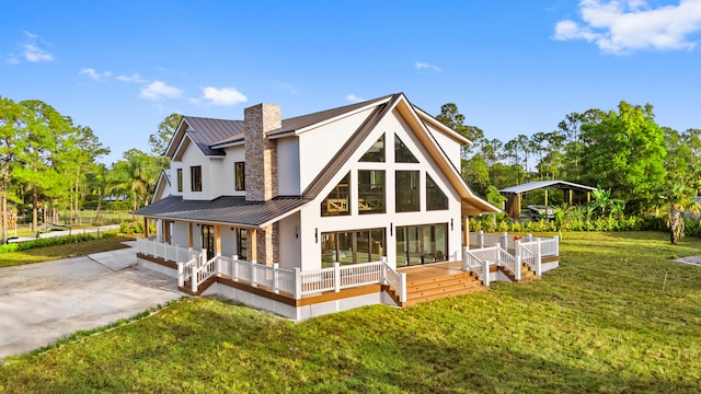13613 157th Ct N, Jupiter, FL 33478 - rear view of property featuring a lawn, a porch, a standing seam roof, stucco siding, and a chimney