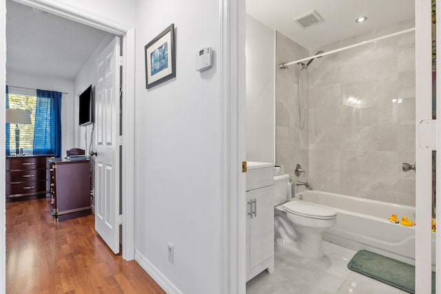 full bathroom with hardwood / wood-style flooring, tiled shower / bath combo, toilet, and vanity