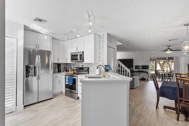 kitchen with white cabinetry, hanging light fixtures, kitchen peninsula, stainless steel appliances, and backsplash