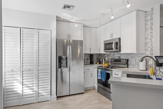 kitchen with decorative backsplash, a textured ceiling, stainless steel appliances, sink, and white cabinetry