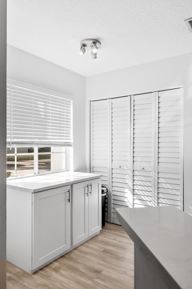 kitchen featuring white cabinetry, a textured ceiling, and light wood-type flooring