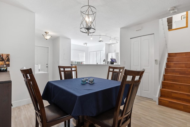 dining area with a textured ceiling and light hardwood / wood-style flooring