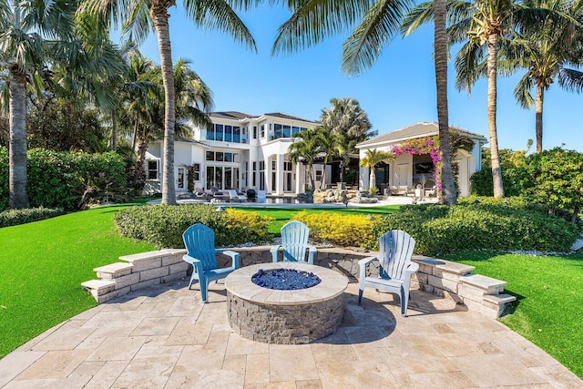 rear view of property with a lawn, a patio, and an outdoor fire pit