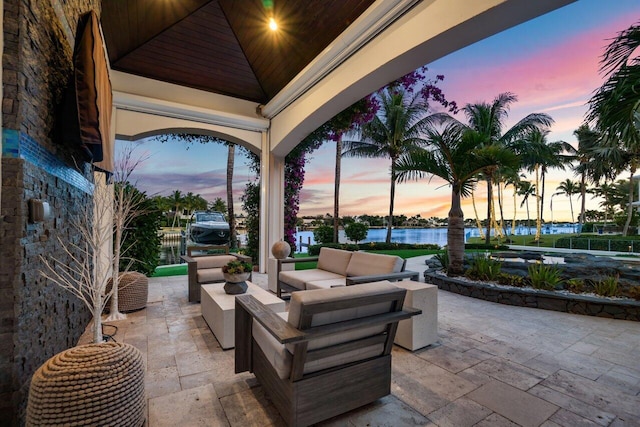 patio terrace at dusk with outdoor lounge area and a water view