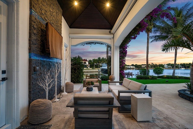 patio terrace at dusk featuring outdoor lounge area and a water view