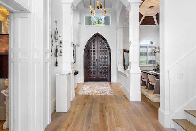 entryway featuring decorative columns, light hardwood / wood-style flooring, plenty of natural light, and ornamental molding