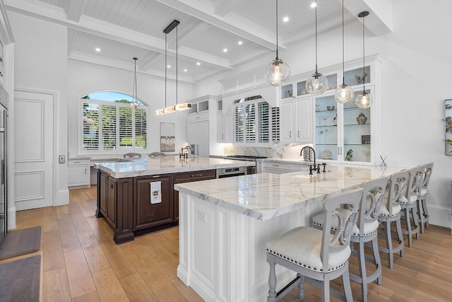 kitchen with a kitchen breakfast bar, white cabinetry, pendant lighting, and light stone counters