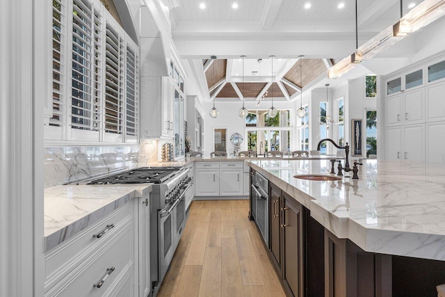 kitchen featuring sink, pendant lighting, double oven range, white cabinets, and light hardwood / wood-style floors