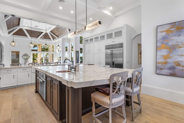 kitchen with a large island, sink, stainless steel appliances, light hardwood / wood-style floors, and white cabinets