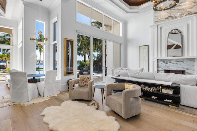 living room with a wealth of natural light, a towering ceiling, and light hardwood / wood-style floors