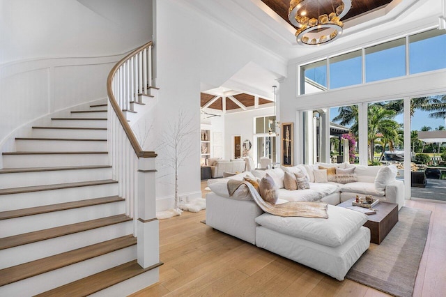 living room with a raised ceiling, a chandelier, light hardwood / wood-style floors, and a high ceiling