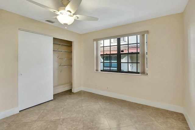 unfurnished bedroom with light tile patterned floors, a closet, and ceiling fan