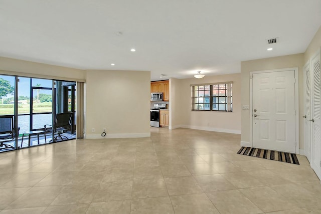 unfurnished living room featuring light tile patterned floors, a water view, and a wealth of natural light