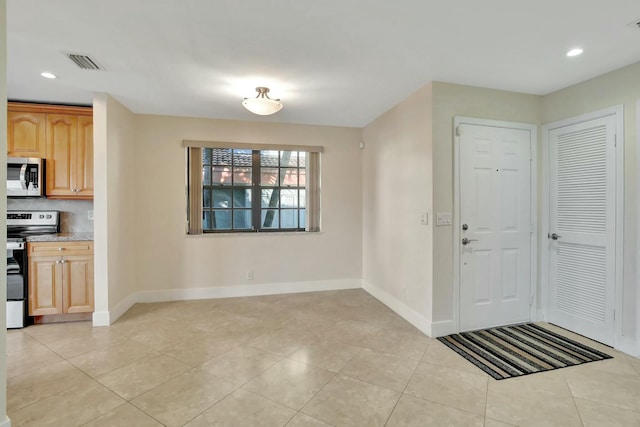 interior space featuring stainless steel range with electric stovetop, light tile patterned flooring, and backsplash