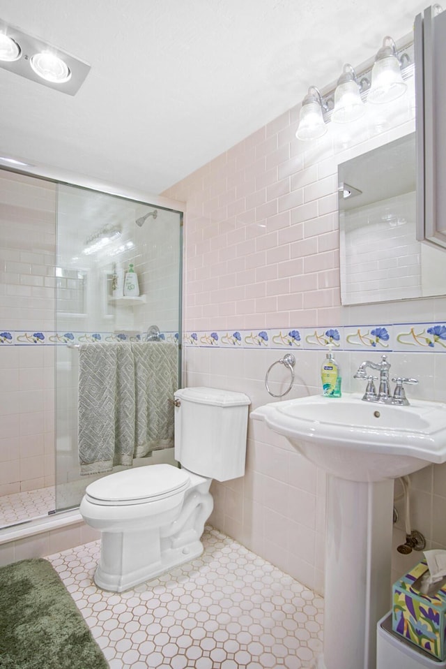 bathroom with tile patterned floors, toilet, tile walls, and walk in shower