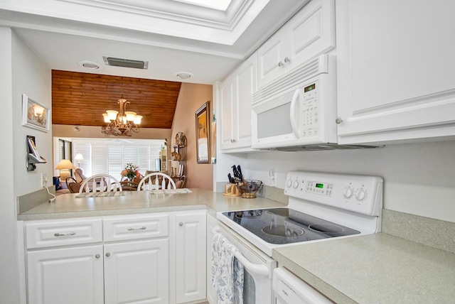 kitchen featuring white appliances, white cabinetry, hanging light fixtures, and a notable chandelier