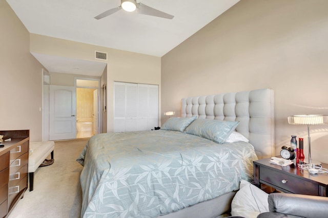 bedroom with ceiling fan, a closet, light carpet, and vaulted ceiling