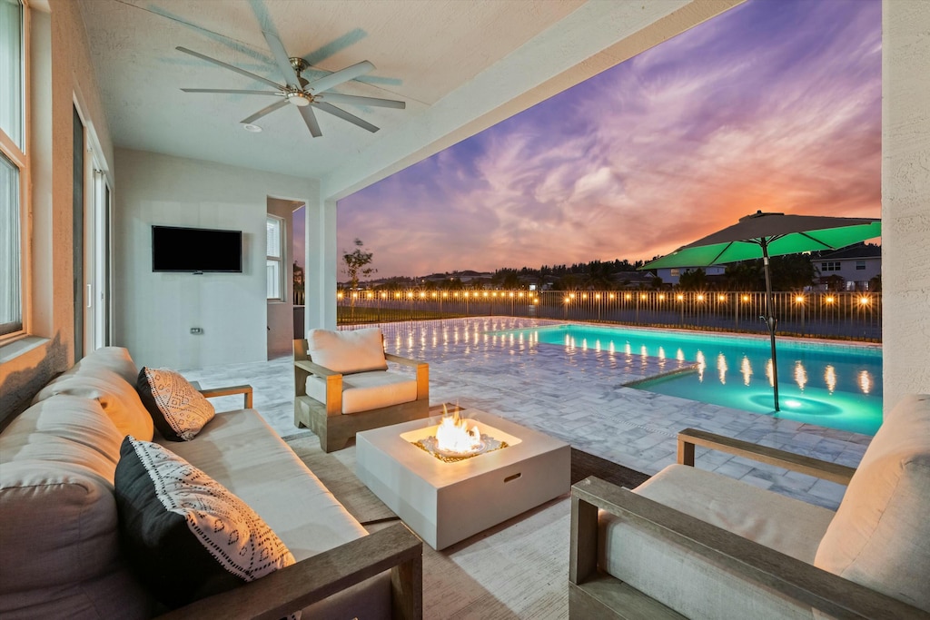 view of pool with ceiling fan, a patio, and an outdoor living space with a fire pit