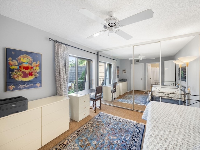 bedroom featuring ceiling fan, light wood-type flooring, a textured ceiling, and a closet