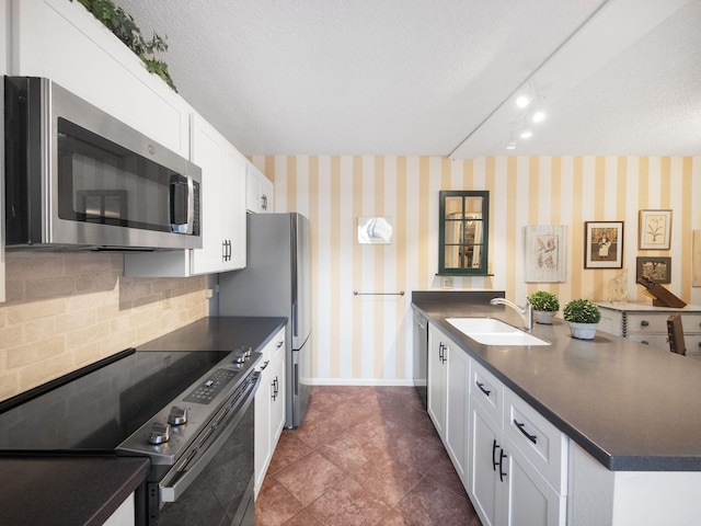 kitchen featuring appliances with stainless steel finishes, tasteful backsplash, a textured ceiling, sink, and white cabinetry