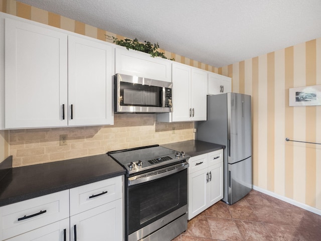 kitchen with white cabinets, appliances with stainless steel finishes, a textured ceiling, and decorative backsplash