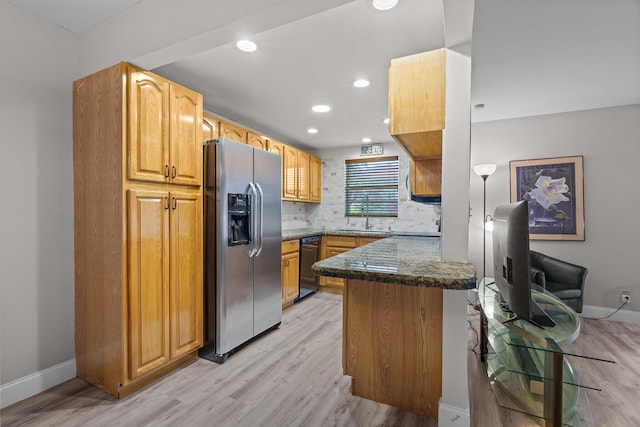 kitchen featuring sink, stainless steel fridge, dark stone countertops, light wood-type flooring, and black dishwasher