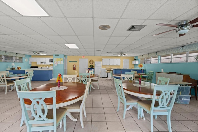 tiled dining space featuring a drop ceiling