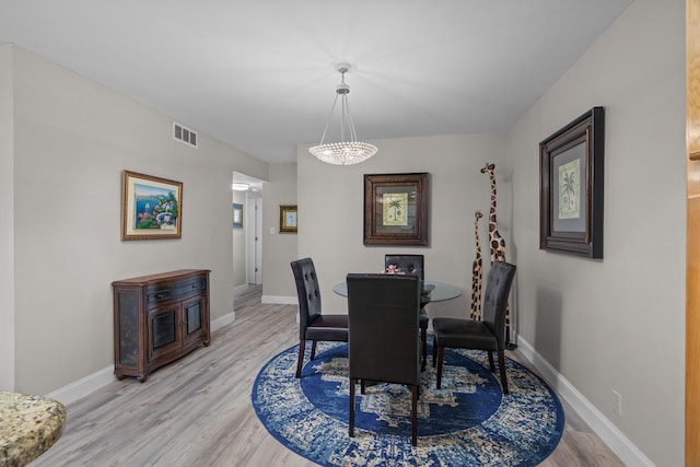 dining space with a notable chandelier and light wood-type flooring