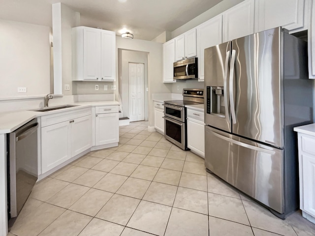 kitchen with light tile patterned flooring, sink, white cabinets, and stainless steel appliances