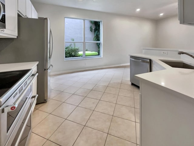 kitchen with white cabinets, sink, light tile patterned floors, and stainless steel appliances