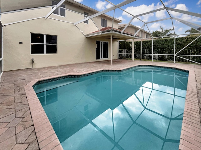 view of pool with a patio area, ceiling fan, and glass enclosure