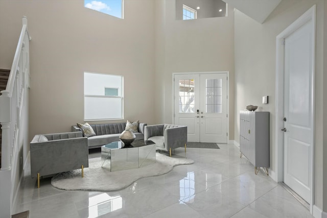 living room featuring a healthy amount of sunlight, a towering ceiling, and french doors