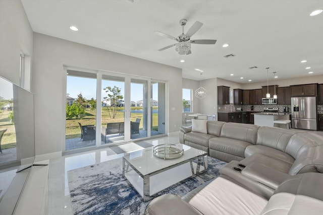 tiled living room featuring ceiling fan with notable chandelier