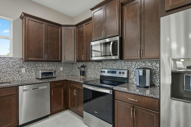 kitchen featuring decorative backsplash, dark brown cabinetry, stainless steel appliances, and dark stone countertops